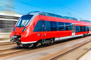 Railroad travel and railway tourism transportation industrial concept: scenic summer view of modern high speed passenger commuter train on tracks with motion blur effect